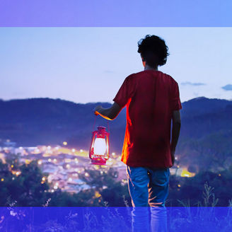 Man holding lantern on a hill over-looking over lit up city