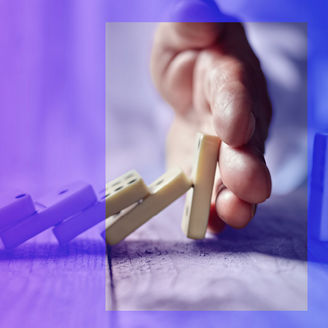 Man’s hand stopping chain of dominos from falling
