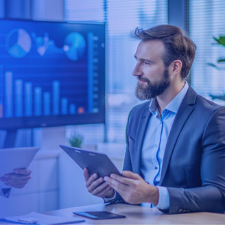 un hombre y una mujer frente a un monitor revisando estados financieros
