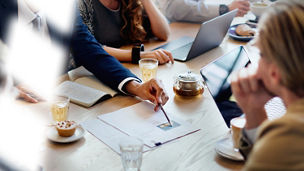 A group of people at a table, with tablets and papers on the table