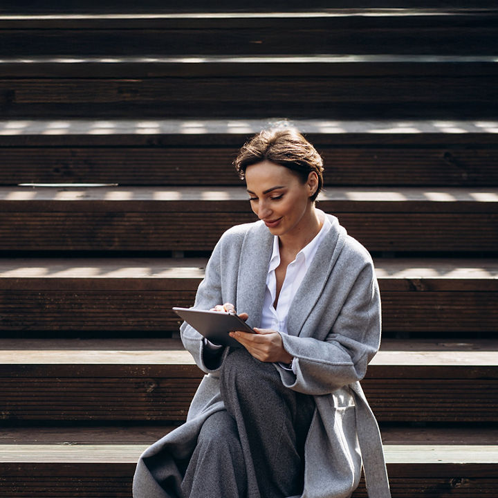 Kobieta siedząca na schodzach, czytająca artykuł na tablecie