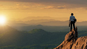 Man on mountain looking at sunset