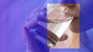 A woman drinking water in a glass.