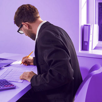 A man is working on his laptop with a calculator next to him