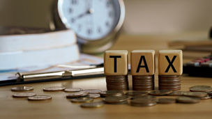Piles of coins with the letters ‘TAX’ in blocks written on them.