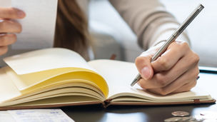 Someone is writing something down in a notebook