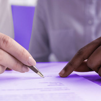 Two people are sitting together, pointing at something on a piece of paper.