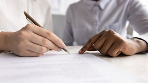Two people are sitting together, pointing at something on a piece of paper.