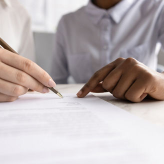 Two people are sitting together, pointing at something on a piece of paper.