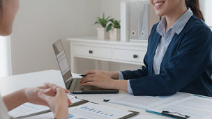 People sitting at a table with papers and typing on a laptop