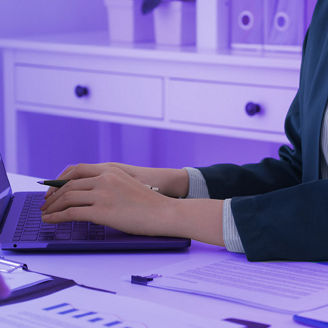 People sitting at a table with papers and typing on a laptop