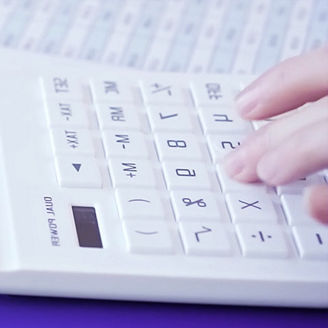 People are sitting at a table with papers and calculators on the table.