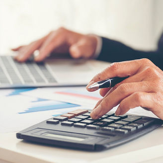 A mans hand is typing something on a calculator