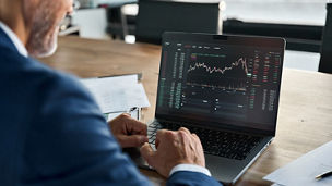 Man looking at stats and graphs on laptop