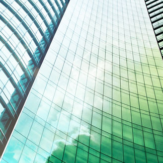 A picture taken from the bottom of a glass building, facing upwards