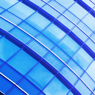 A picture taken from the bottom of a glass building, facing upwards