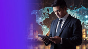 A man in a suit holding and looking at a tablet, with a translucent world map and connecting lines displayed behind them and a blurred cityscape in the background