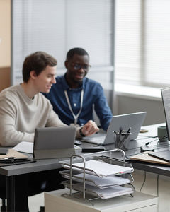 Drei Männer sitzen an ihren Laptops und halten eine Besprechung über Cyber Security in Behörden ab