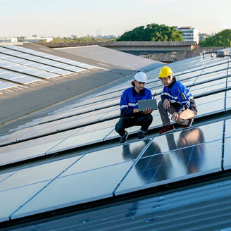 Two solar panel technician are holding laptop next to solar panels