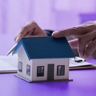 Person looking at a 3D model house and checking notes