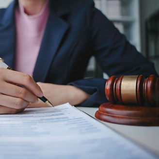 A woman is writing something down on paper next to a judge’s gavel.