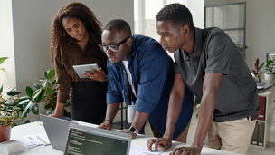 African American coworkers looking at codes together, they focused on working process