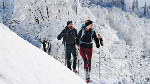 Man and woman walking on mountain ridge.