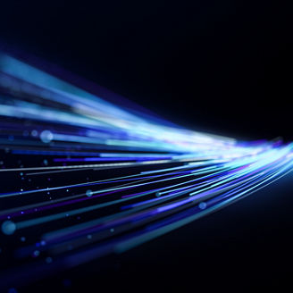 Futuristic blue and cyan light streaks curve across a dark background toward a bright focal point, creating a dynamic concept of high-speed data flow, connectivity, and digital technology.