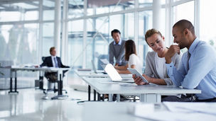 Business colleagues discussing over digital tablet at desk in office