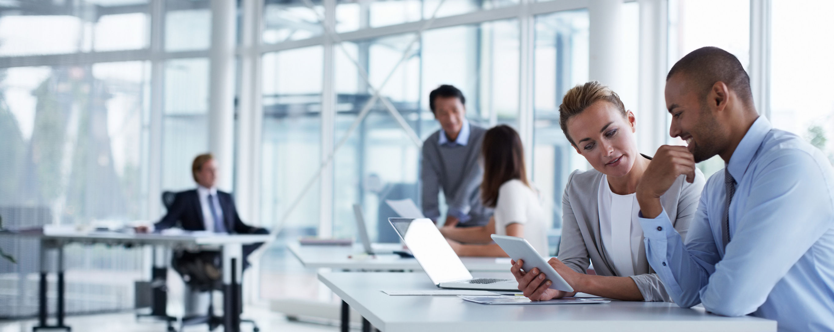 Business colleagues discussing over digital tablet at desk in office