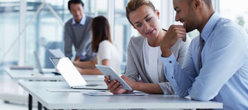 Business colleagues discussing over digital tablet at desk in office