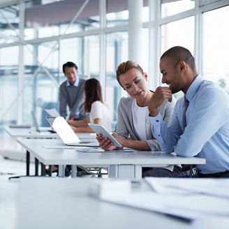 Business colleagues discussing over digital tablet at desk in office