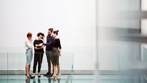 A group of young businesspeople standing near staircase, talking. Copy space.