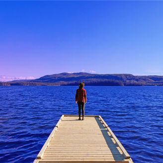 Fotografía de una persona parada a la orilla de un muelle mientras observa el horizonte