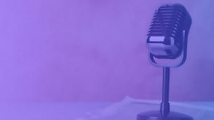 Microfone vintage sobre uma mesa, iluminado por luz suave roxa