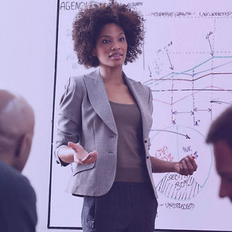 Team meeting with a woman presenting next to a screen.