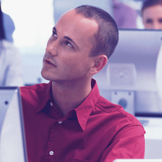 Homem a ouvir instruções de um colega enquanto trabalha num computador.