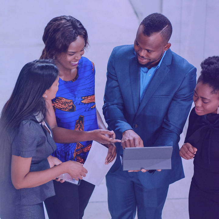 A group of four professionals reviewing information on a tablet in a corporate setting
