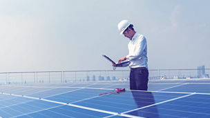 Engenheiro a inspecionar painéis solares num terraço.