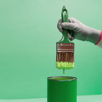 Pinsel voll mit grüner Farbe vor grünen Hintergrund