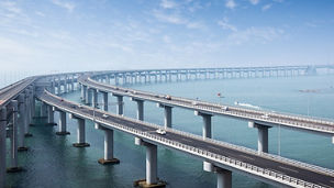 A long suspension bridge stretching over a calm, wide river.
