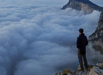 man looking over the cloud on top of a mountain