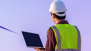 Man with laptop looking at windmill
