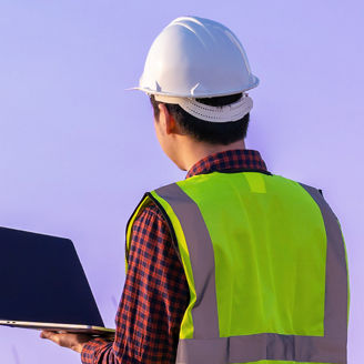 Man with laptop looking at windmill
