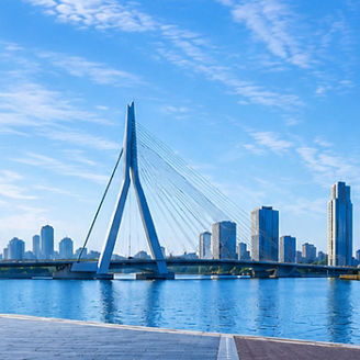 Panoramic waterfront cityscape with a modern bridge, Dutch windmill and historic canal-side buildings.