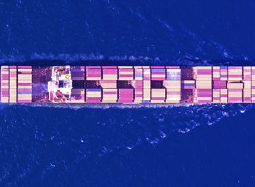 A cargo ship loaded with container sailing on a calm blue sea