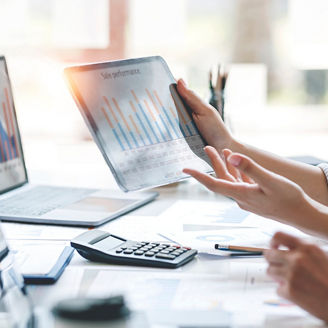 Laptops on tables and hands holding paper