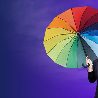 Ein bunter Regenschirm mit verschiedenen Farbfeldern vor einem violetten Hintergrund.