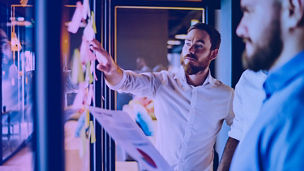 Duas pessoas a olhar para um quadro com post-its