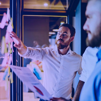 Duas pessoas a olhar para um quadro com post-its